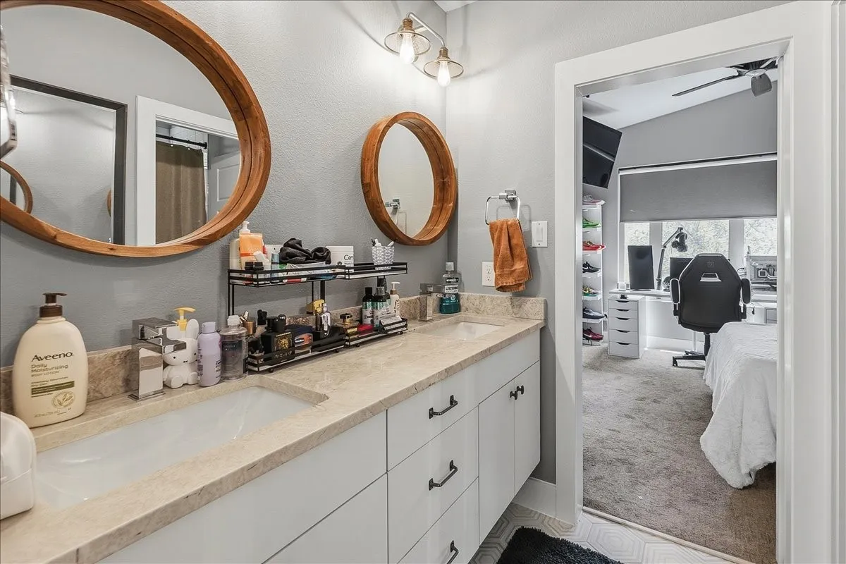 Double vanity with light-toned countertop, dual sinks, and two round wooden-framed mirrors