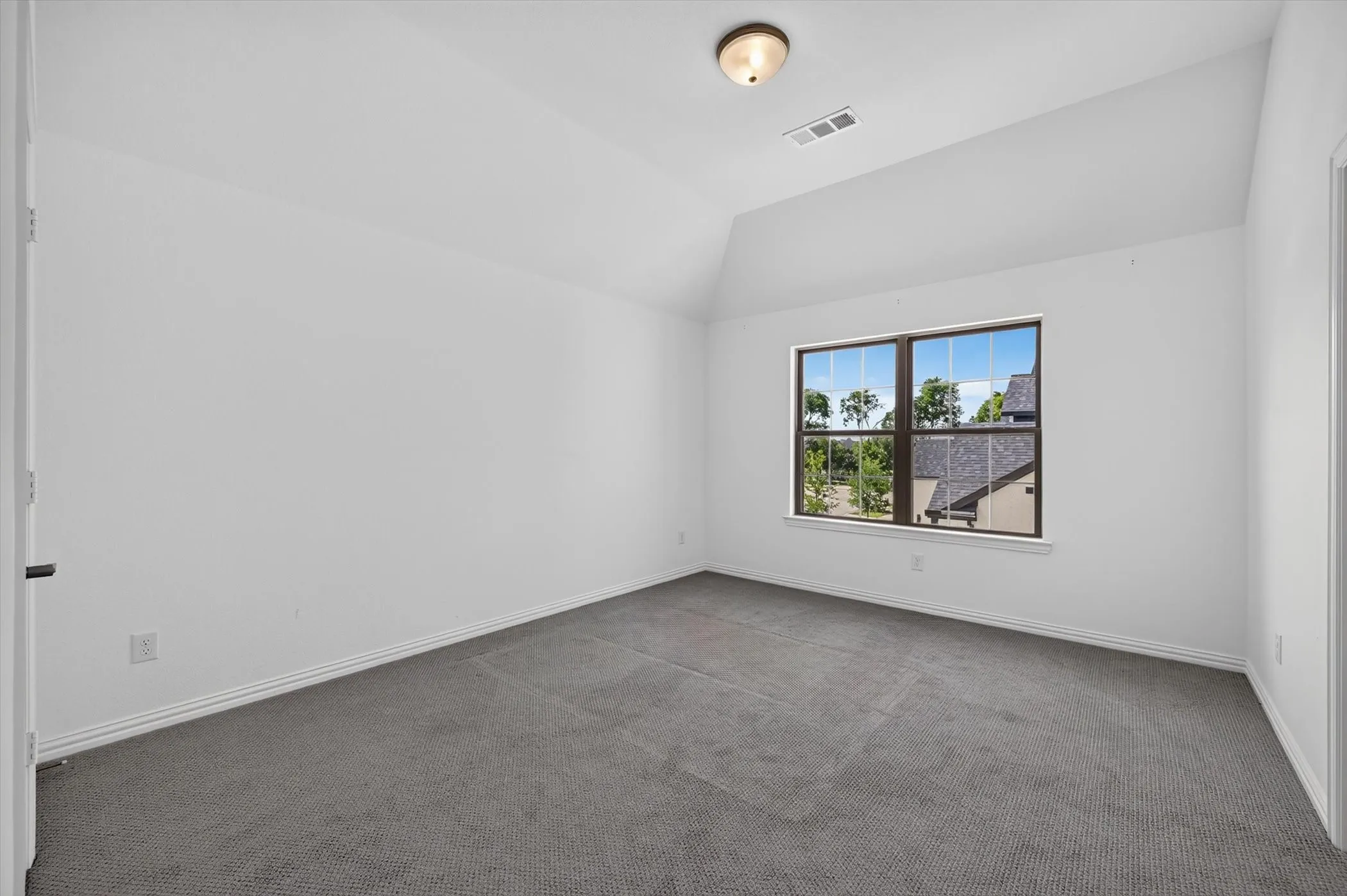Room featuring a window with dark trim, light-colored walls, and gray carpeting