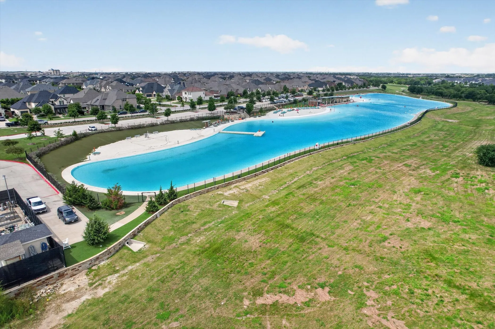 Expansive community lagoon featuring clear blue water and sandy beach areas