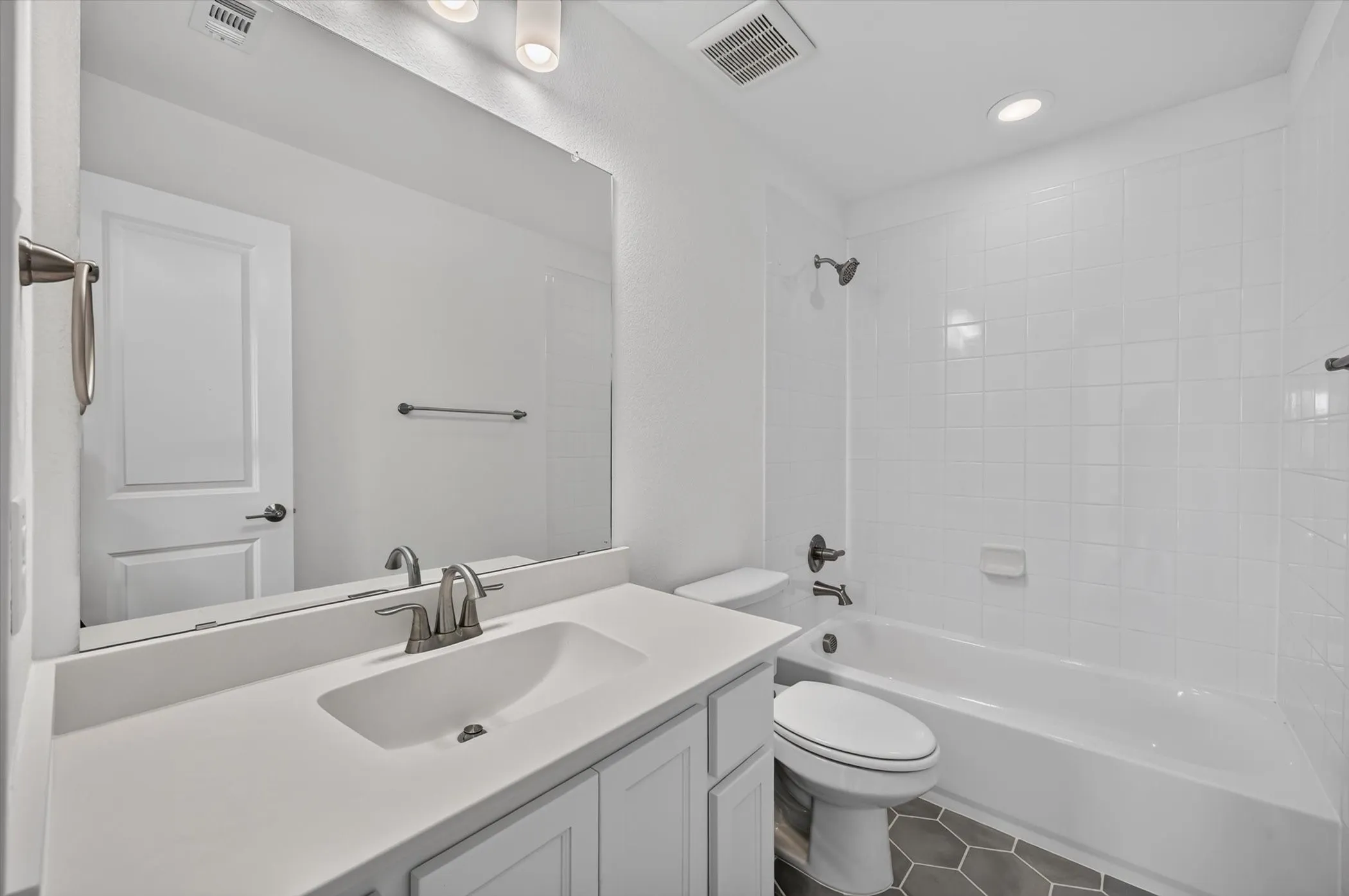 Bathroom featuring a white vanity with an integrated sink, brushed nickel faucet, and a large wall-mounted mirror