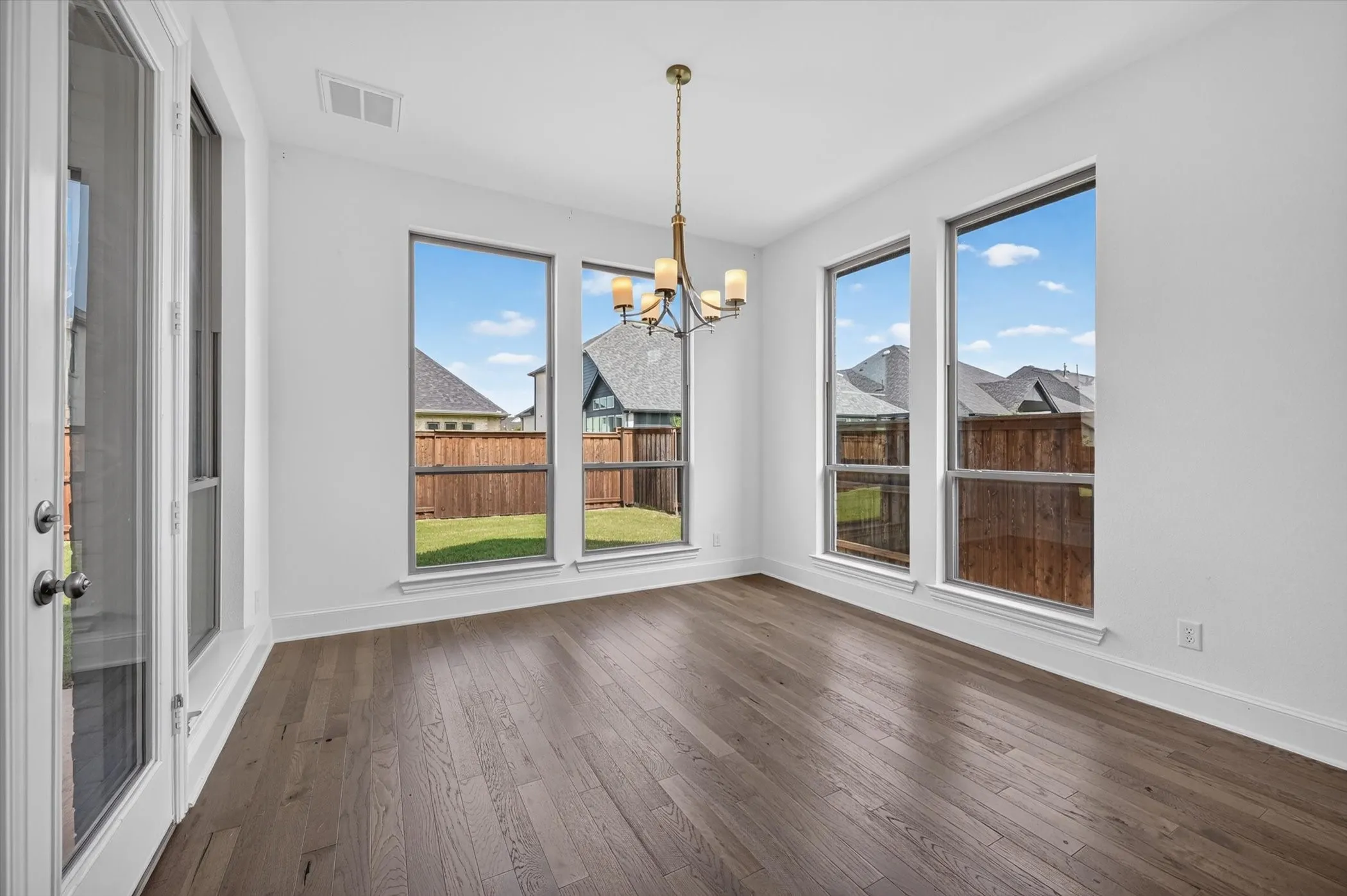 Interior space featuring wood-finish flooring, white walls, and a multi-light chandelier