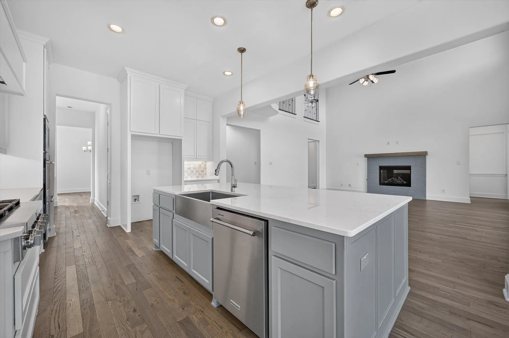 Kitchen island featuring a farmhouse sink, stainless steel dishwasher, and a white countertop