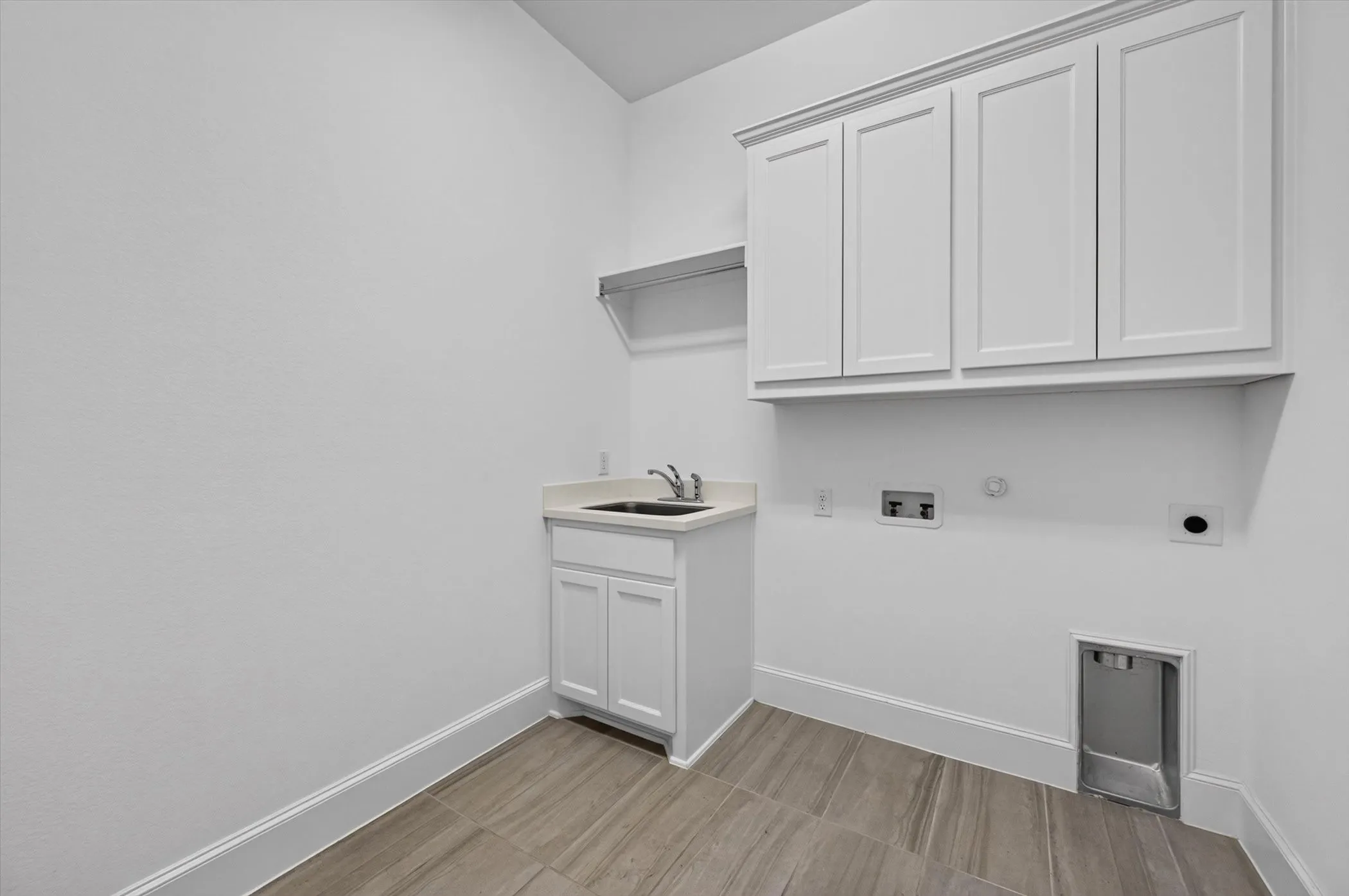 Dedicated utility space featuring a built-in sink, white cabinetry, wood-finish flooring, and wall-mounted shelving