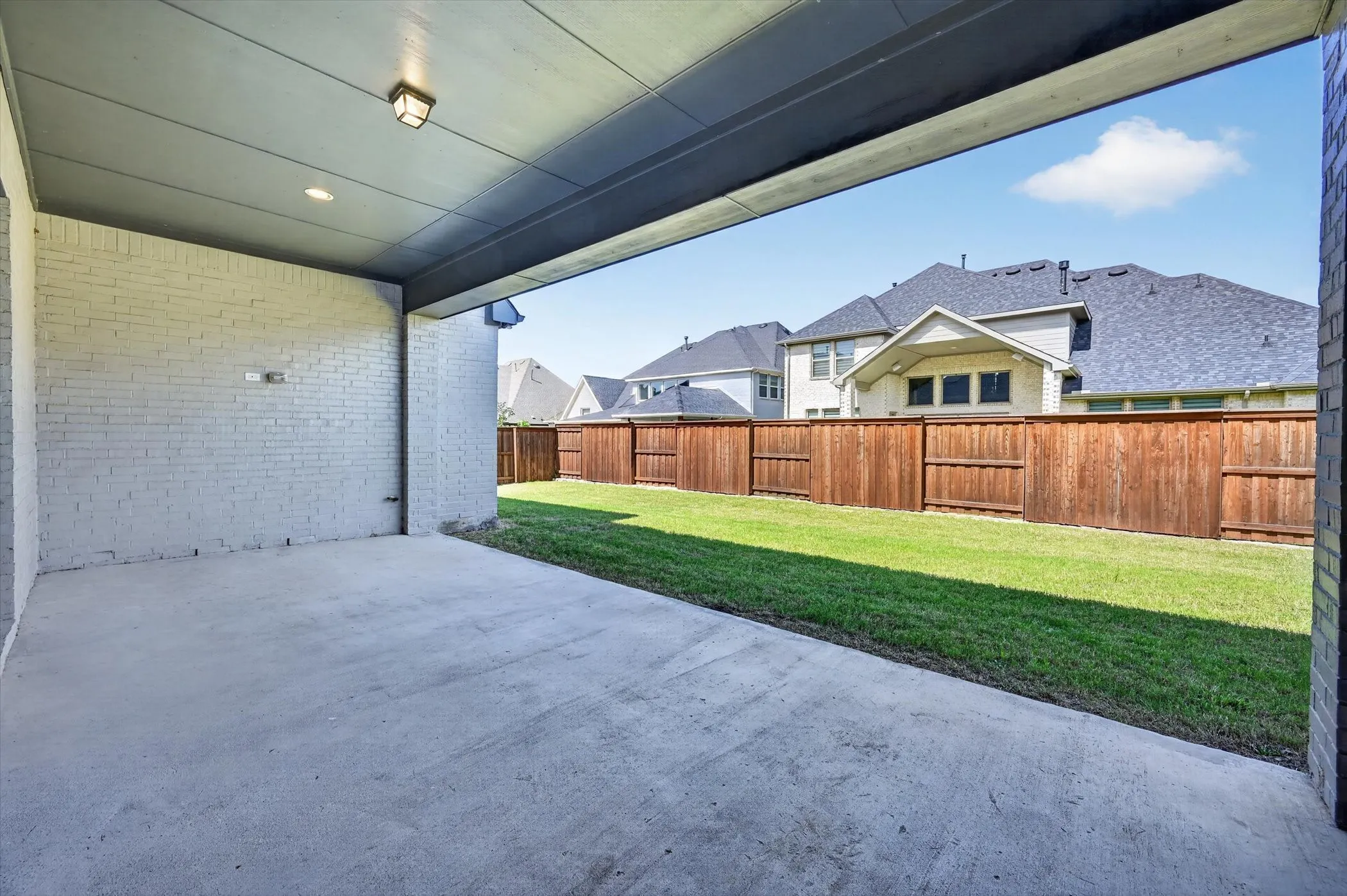 Covered concrete patio featuring recessed lighting and an exterior wall of painted brick