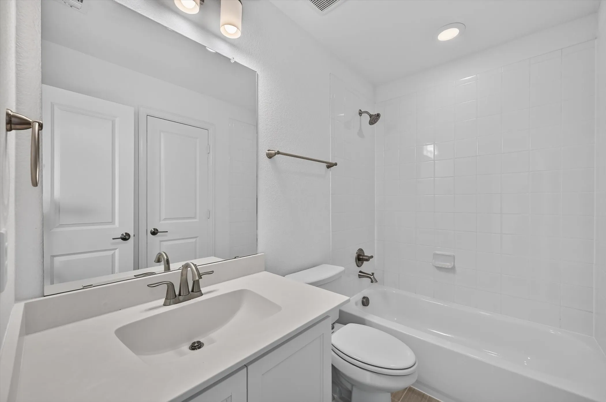 Bathroom featuring a single vanity with an integrated sink, brushed nickel faucet, and overhead lighting