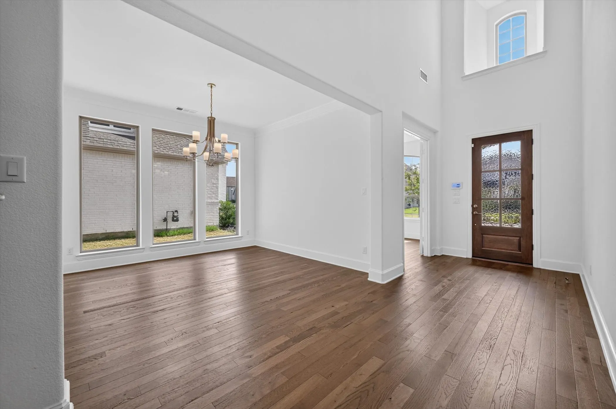 Two-story entryway with a dark wood-finish front door featuring a seeded glass insert
