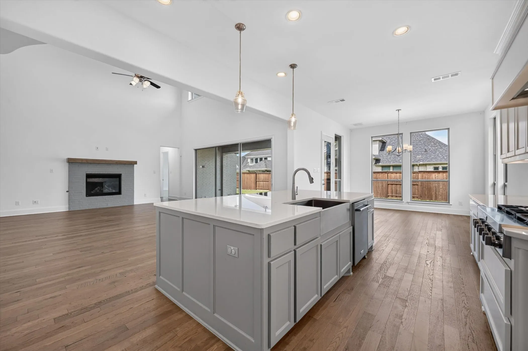 Open-concept kitchen featuring a large island with white countertop, farmhouse sink, and pendant lighting