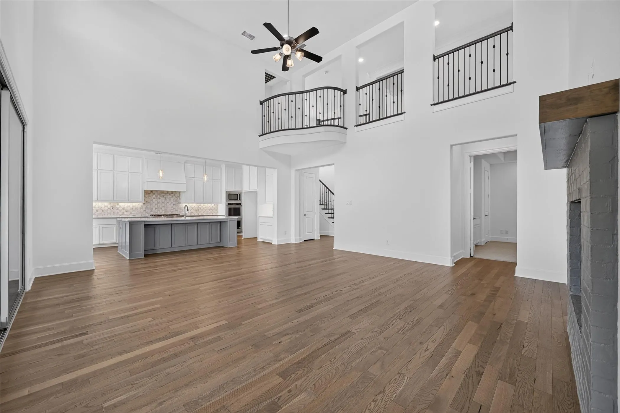 Expansive open-concept interior featuring wood-finish flooring, soaring ceilings, and a modern fireplace with a wood mantel
