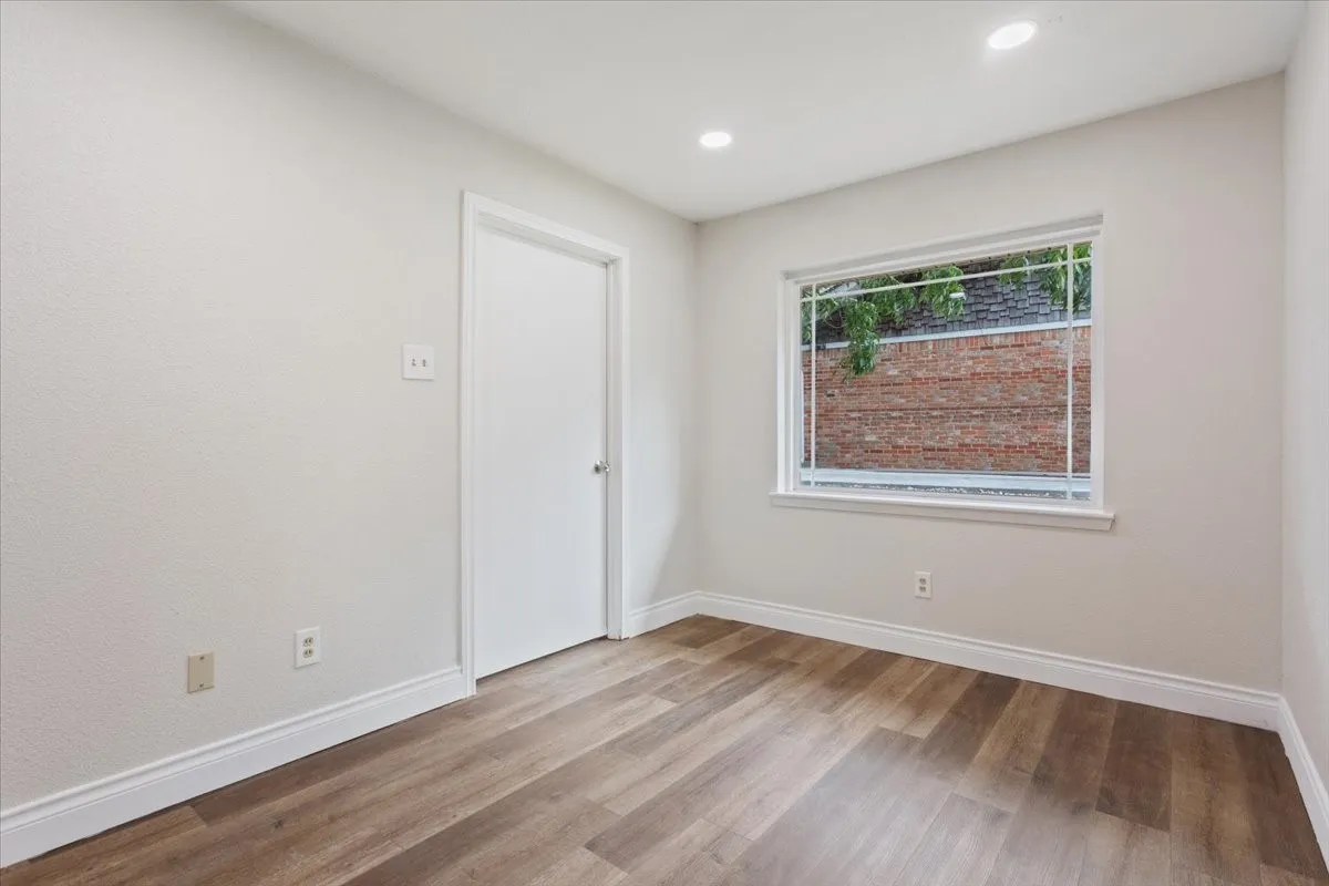 Room featuring wood-finish flooring, recessed lighting, and a white interior door