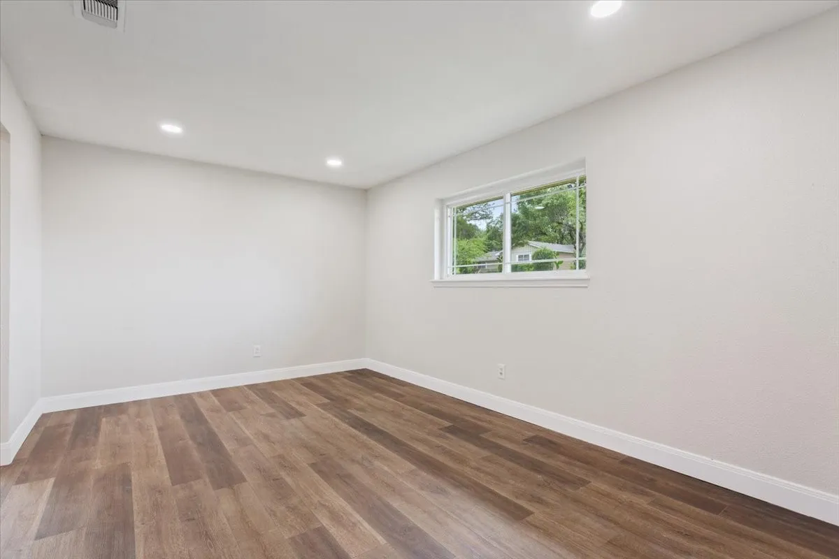 Room with wood-finish flooring, recessed lighting, and a window providing natural illumination