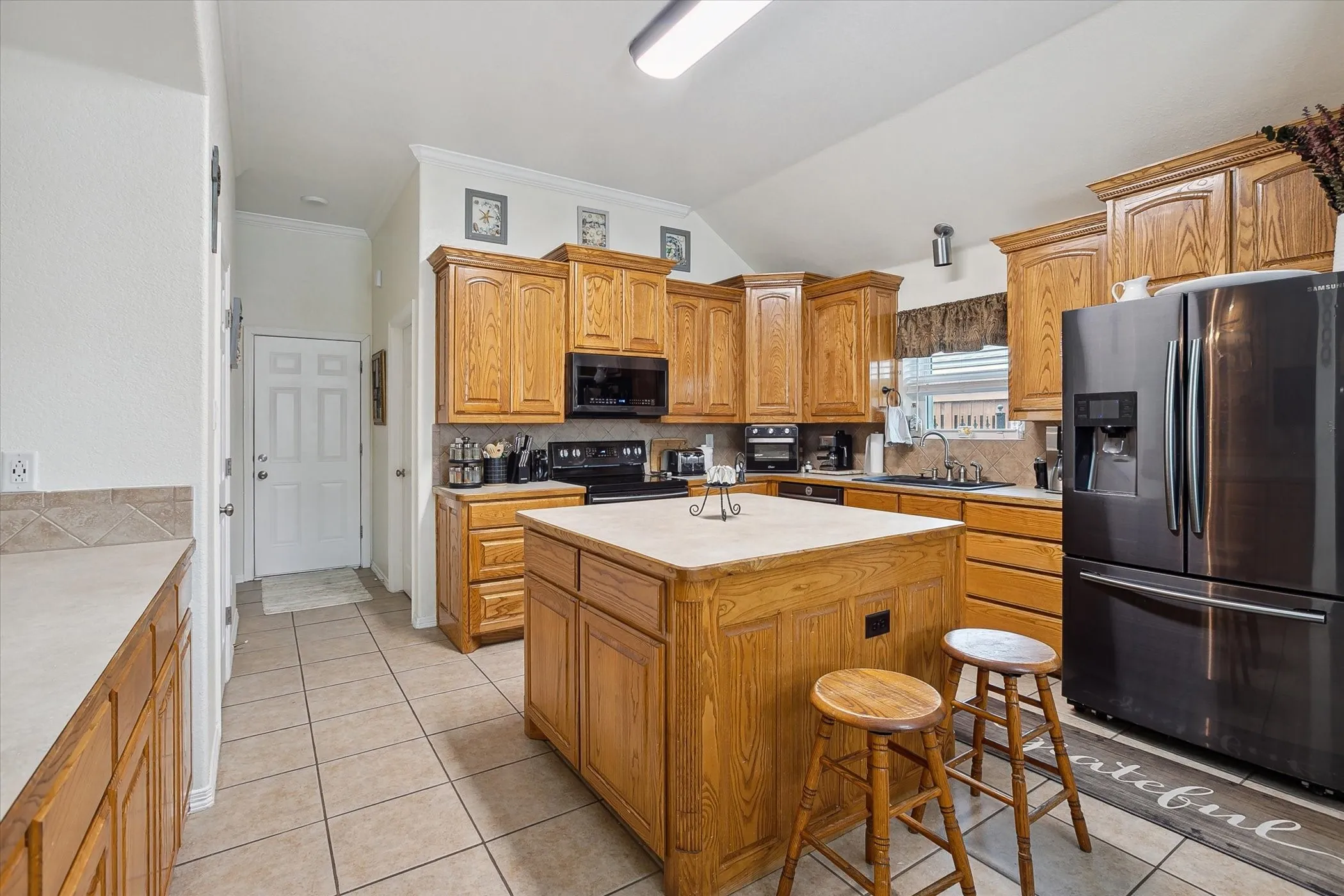 Kitchen featuring a central island with a light-colored countertop, tile flooring, and a tile backsplash