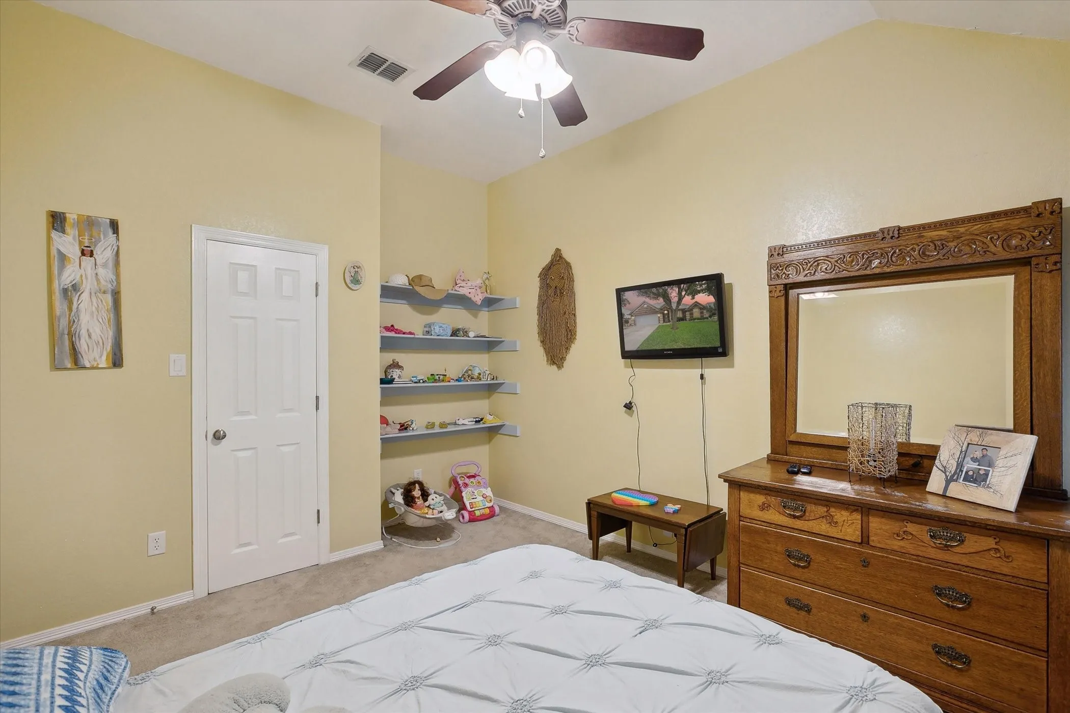 Bedroom with light carpet, shelving and ceiling fan.