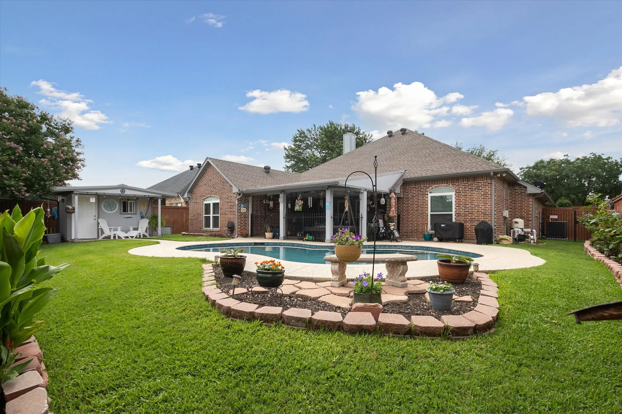 Beautiful backyard with covered patio, pool house, landscaping and sparkling pool