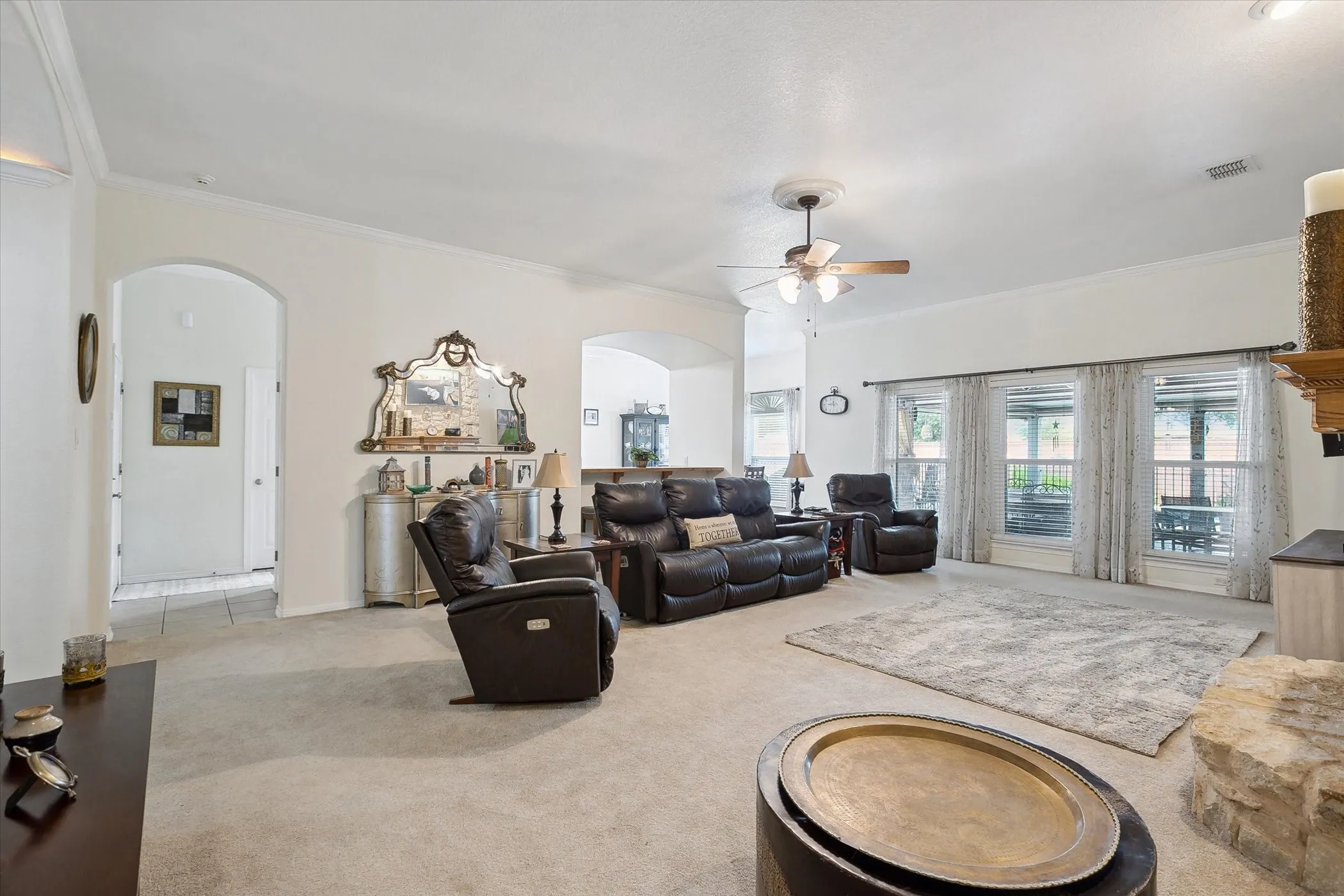 Expansive living area featuring light-colored carpeting, multiple windows providing ample natural light