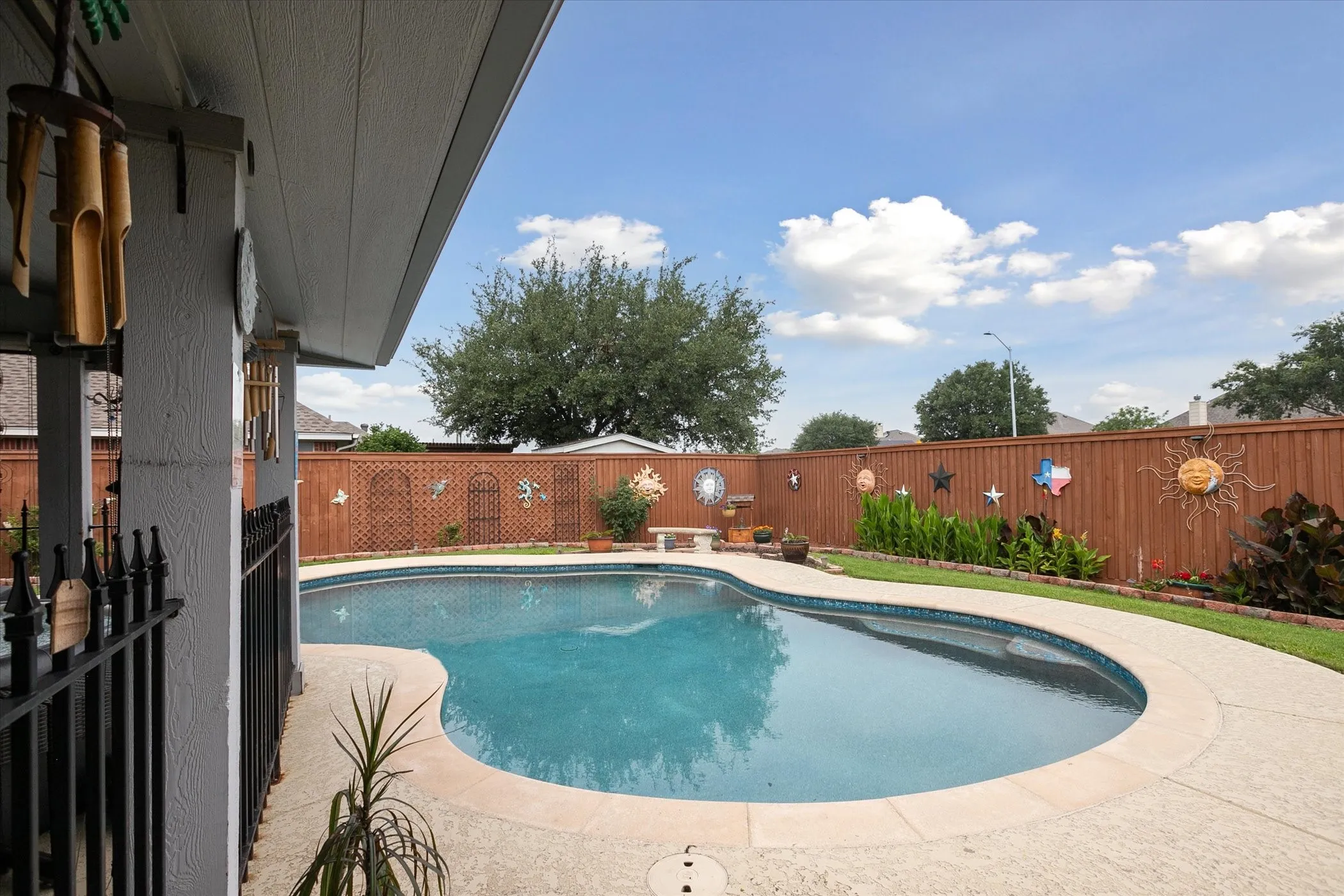 Backyard oasis featuring a swimming pool with concrete decking, and a privacy fence and nice landscaping.