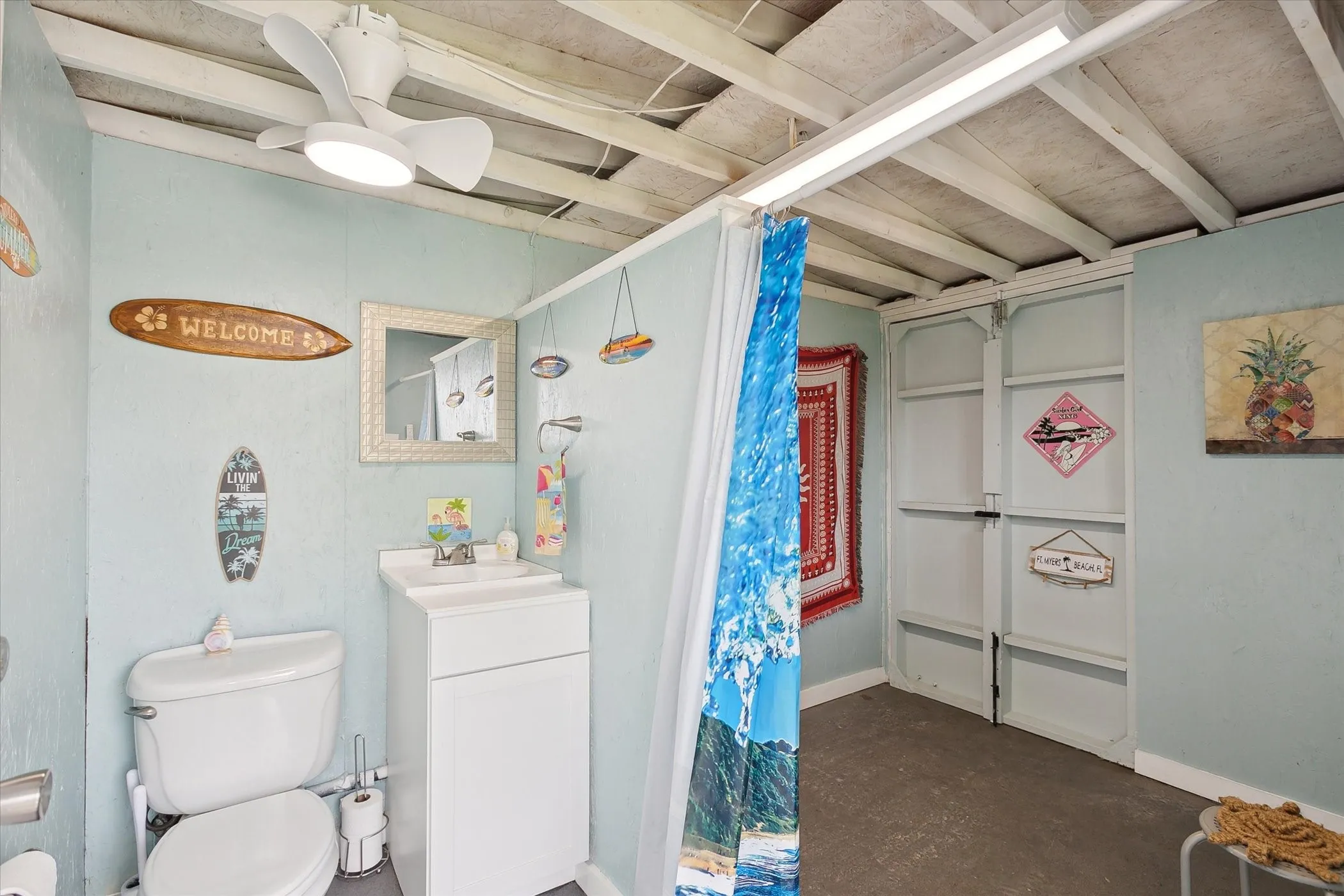  Pool house with sink and toilet, ceiling fan and dressing area.
