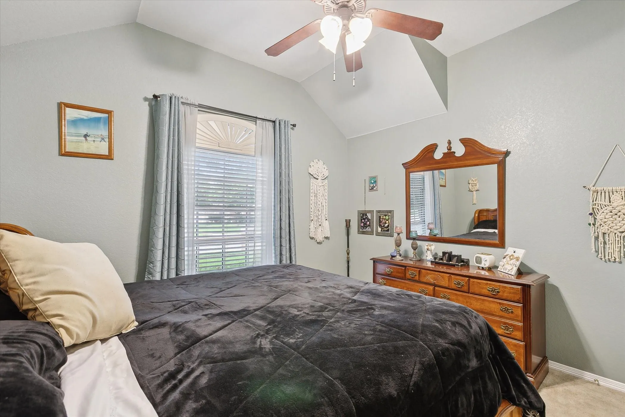 Vaulted ceiling bedroom with a ceiling fan, a window featuring blinds and neutral wall tones