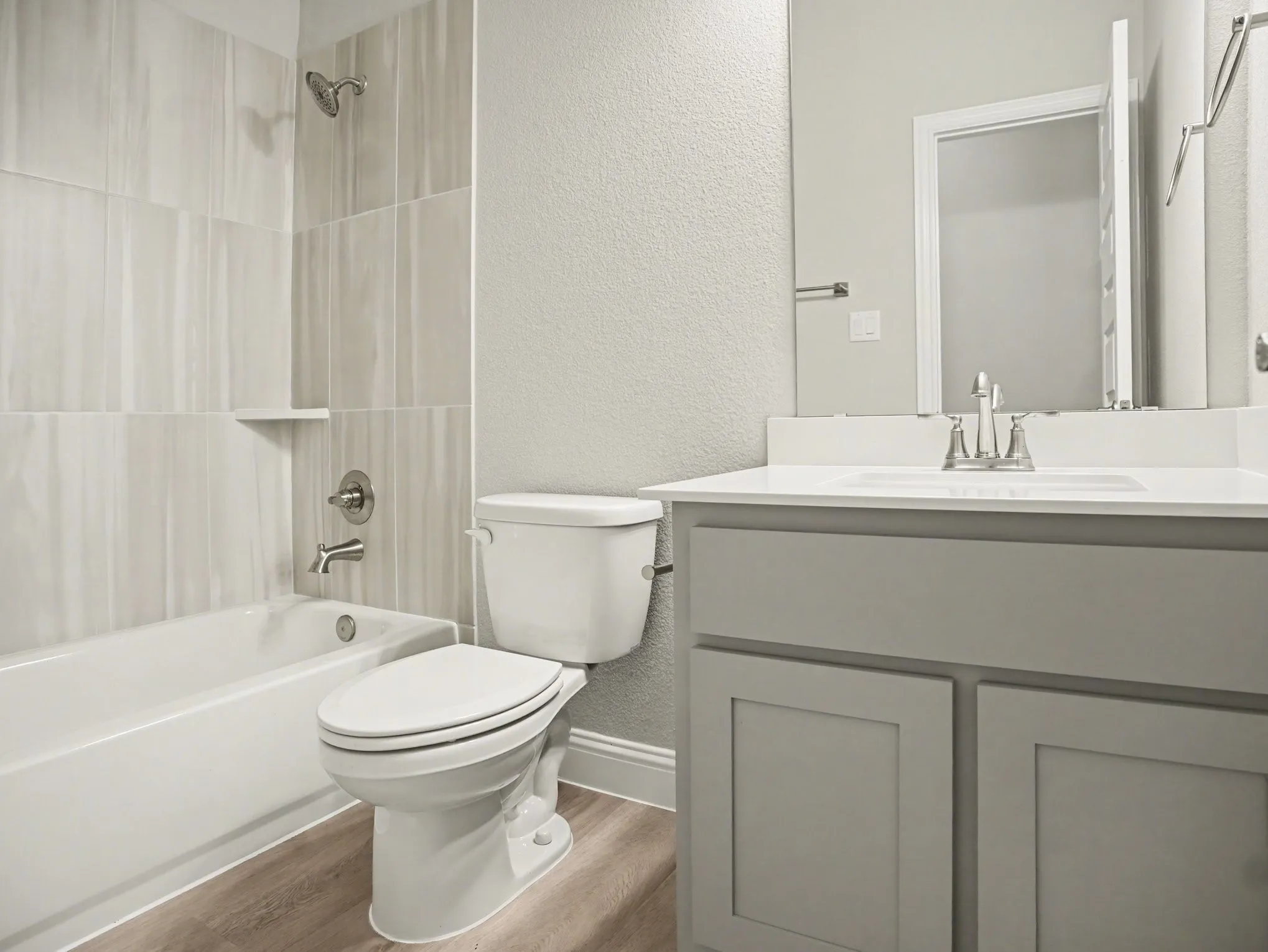 Bathroom featuring a white bathtub, a toilet, and a vanity with a white countertop and gray cabinetry