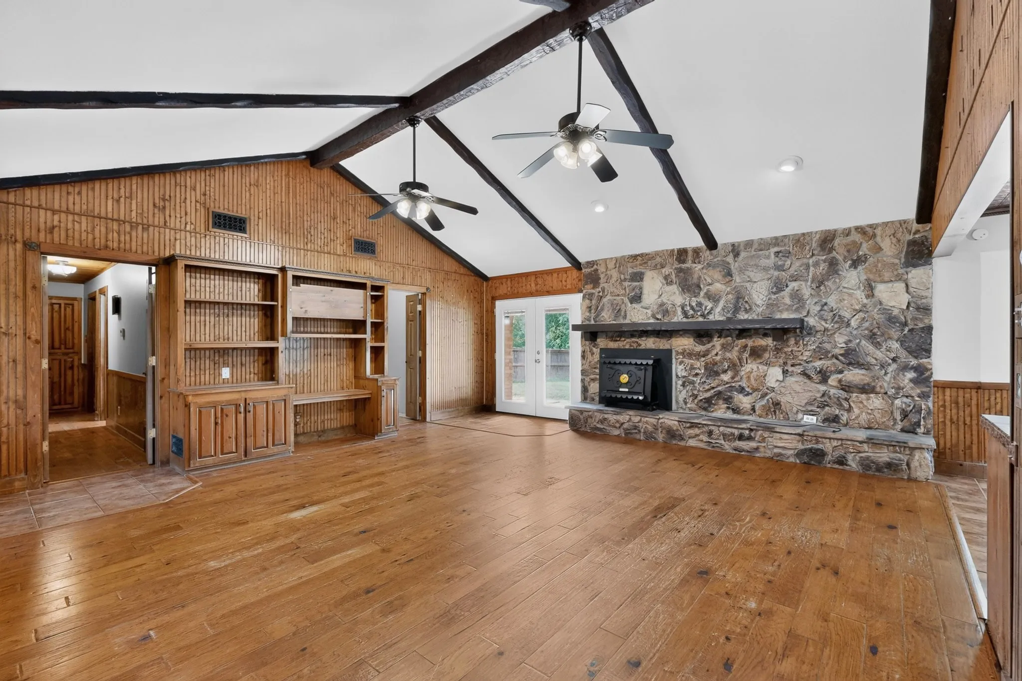 Vaulted ceilings with exposed wood beams complement the natural wood-panel accent wall