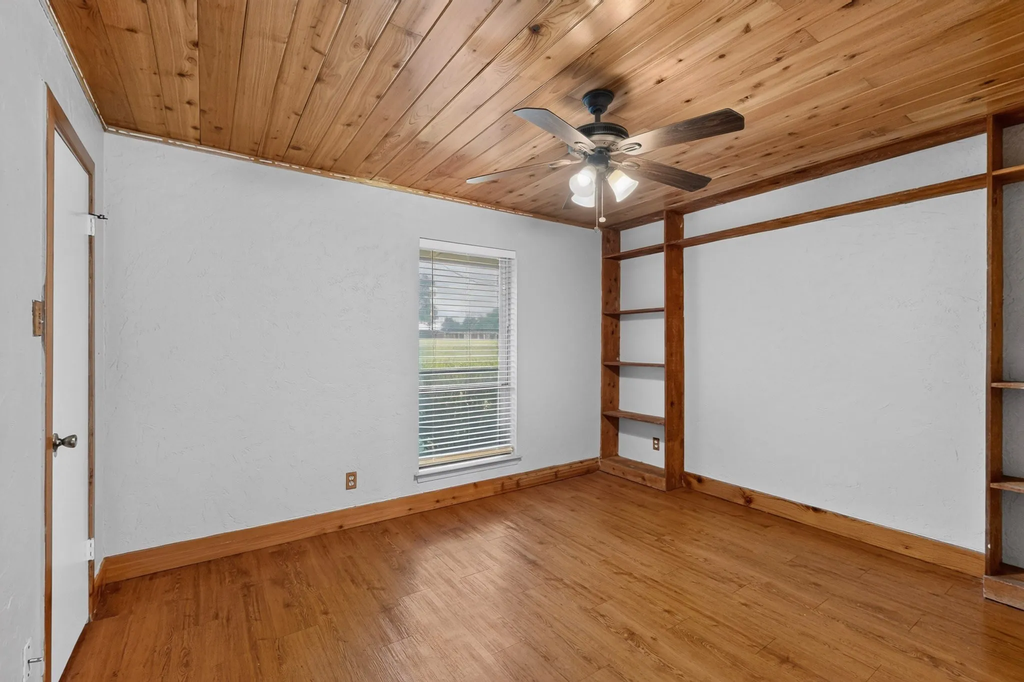 Room featuring a wood-panel ceiling, wood-finish flooring, and white walls