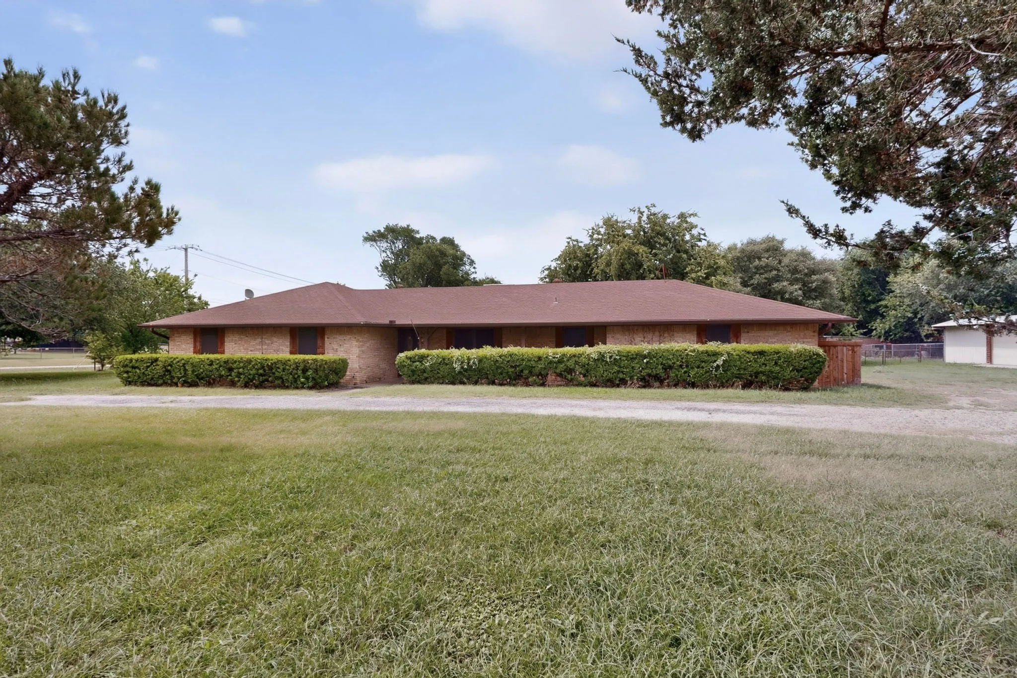 Brick ranch-style exterior with a low-pitch roof and dark brown shingles