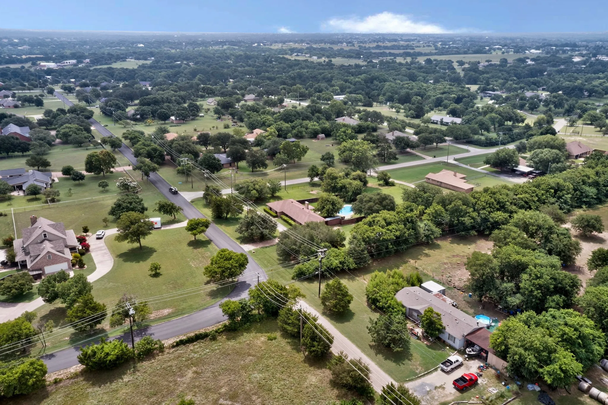 Expansive aerial capturing a neighborhood characterized by mature trees and residential properties
