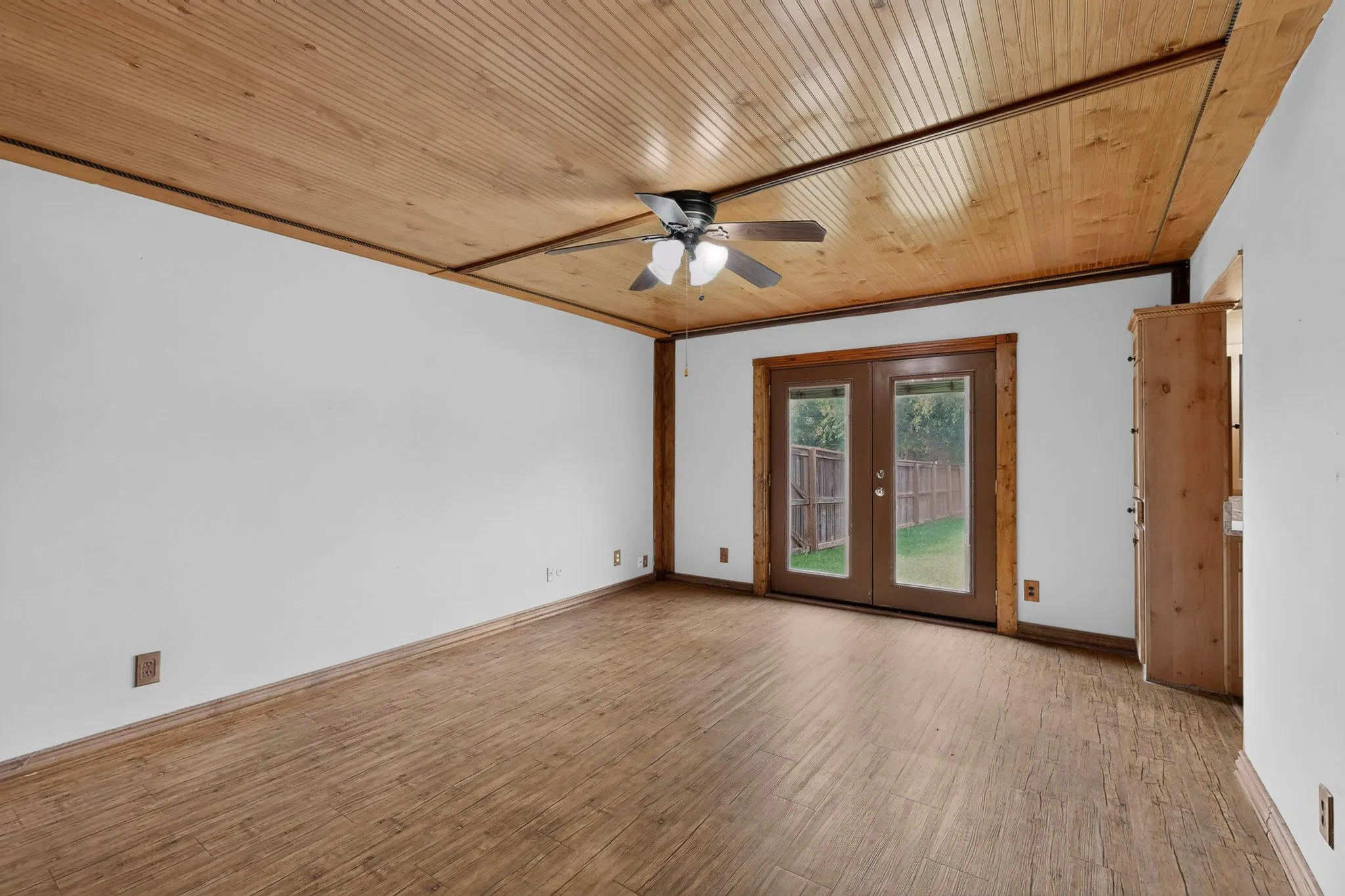 Room featuring a wood-finish plank ceiling with a ceiling fan, light wood-finish flooring, and white walls