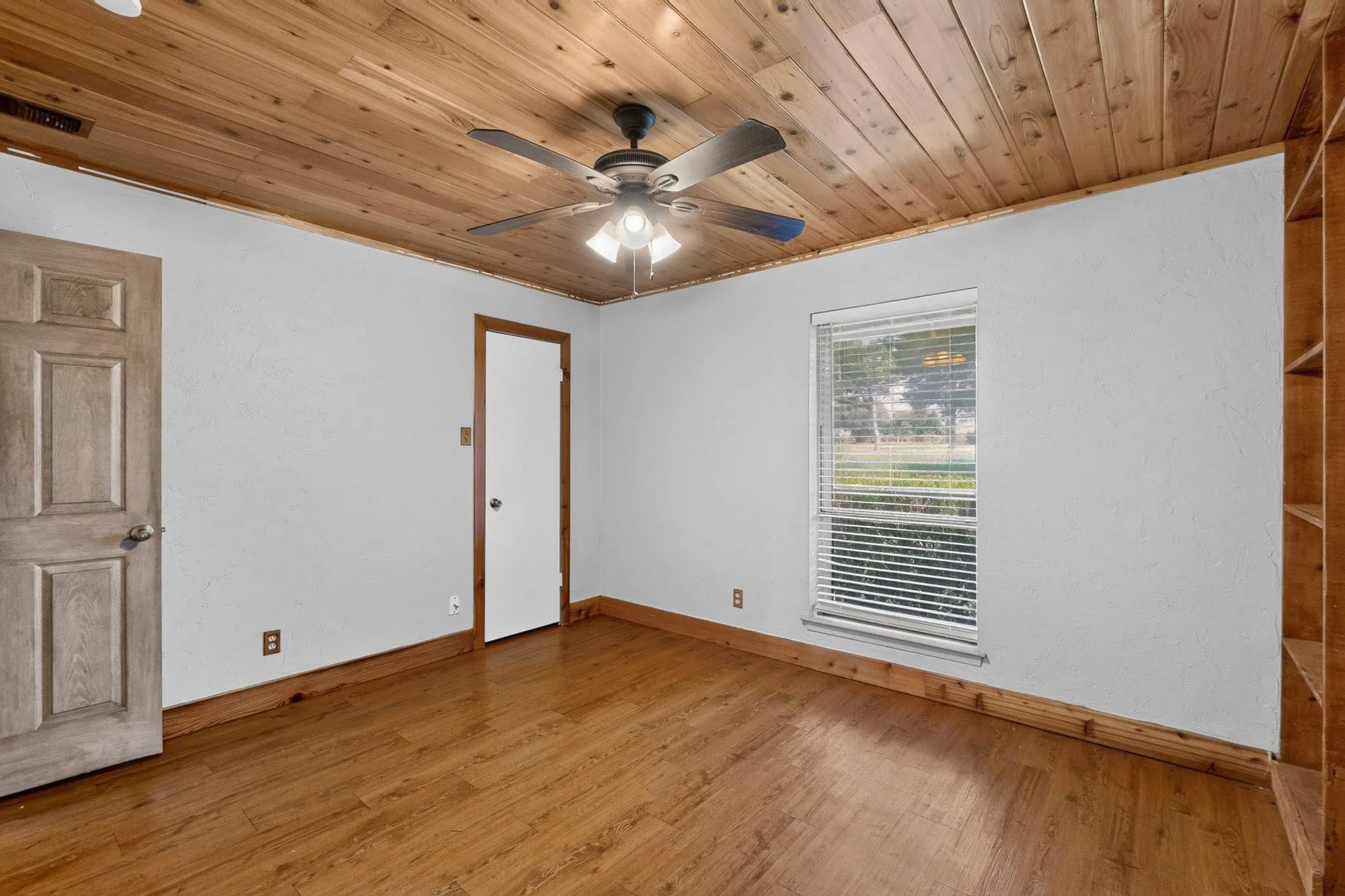 Room featuring a wood-panel ceiling, wood-finish flooring, and white walls