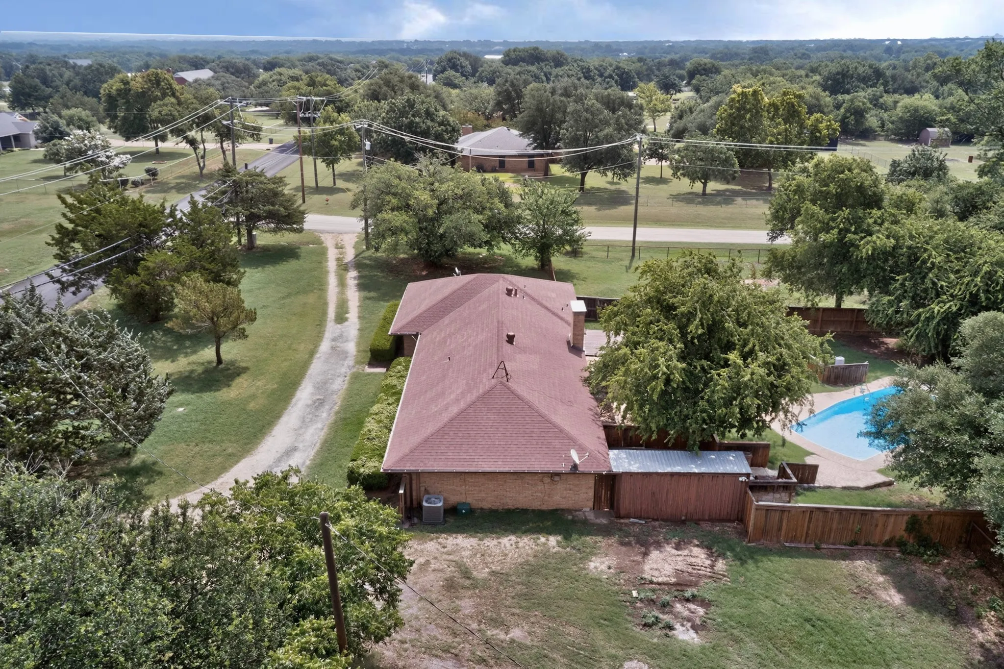 Aerial view showcasing a single-story brick residence with a gabled roof