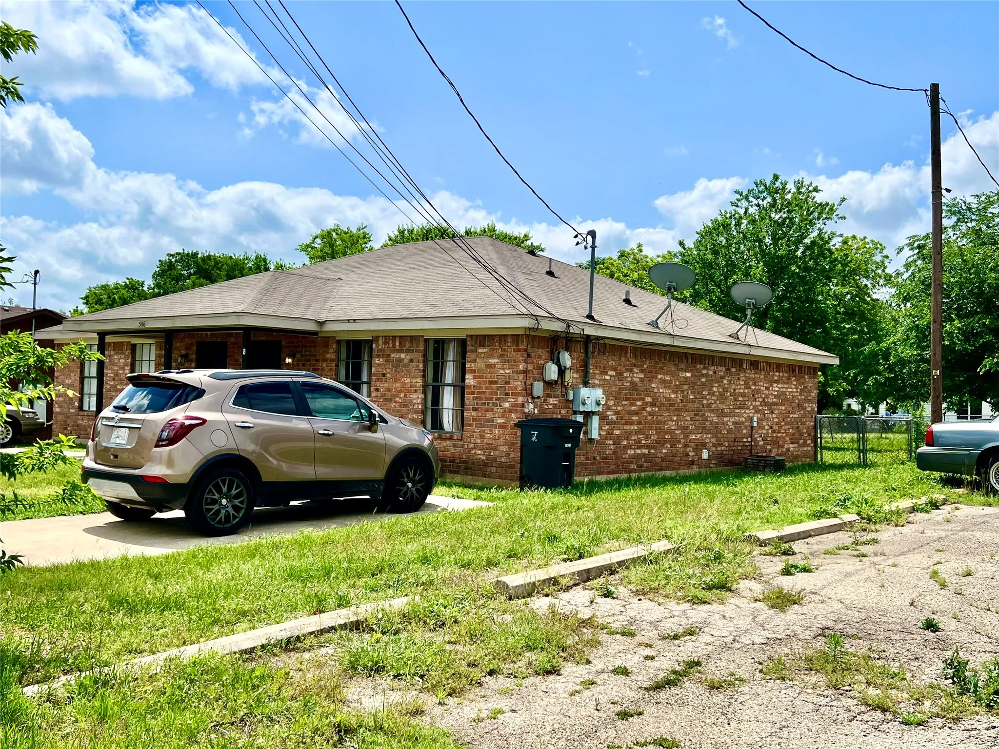 View of property exterior with brick siding and a shingled roof