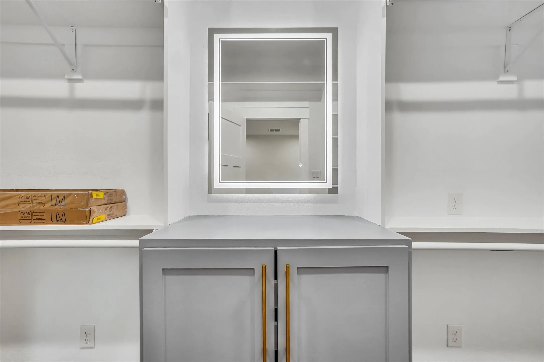 Built-in closet system featuring a central island with gray cabinetry and gold-tone hardware
