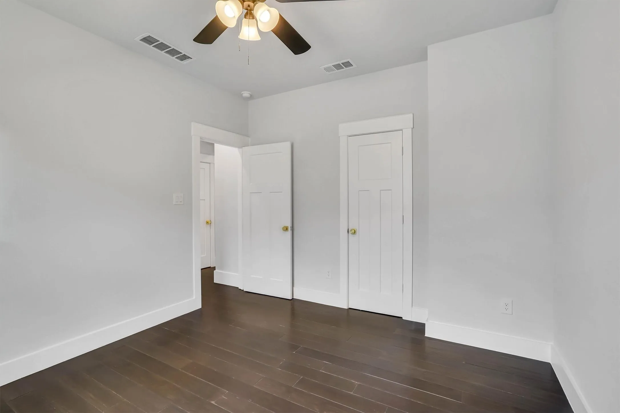 Interior room featuring dark wood-finish flooring, white baseboards, and light gray walls