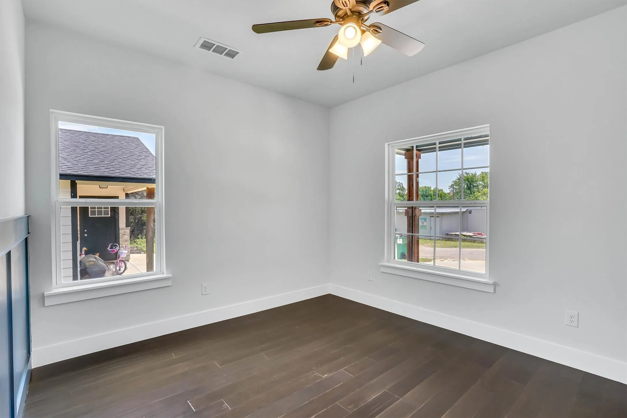 Bright interior featuring dark wood-finish flooring, white walls, and a ceiling fan with integrated lighting