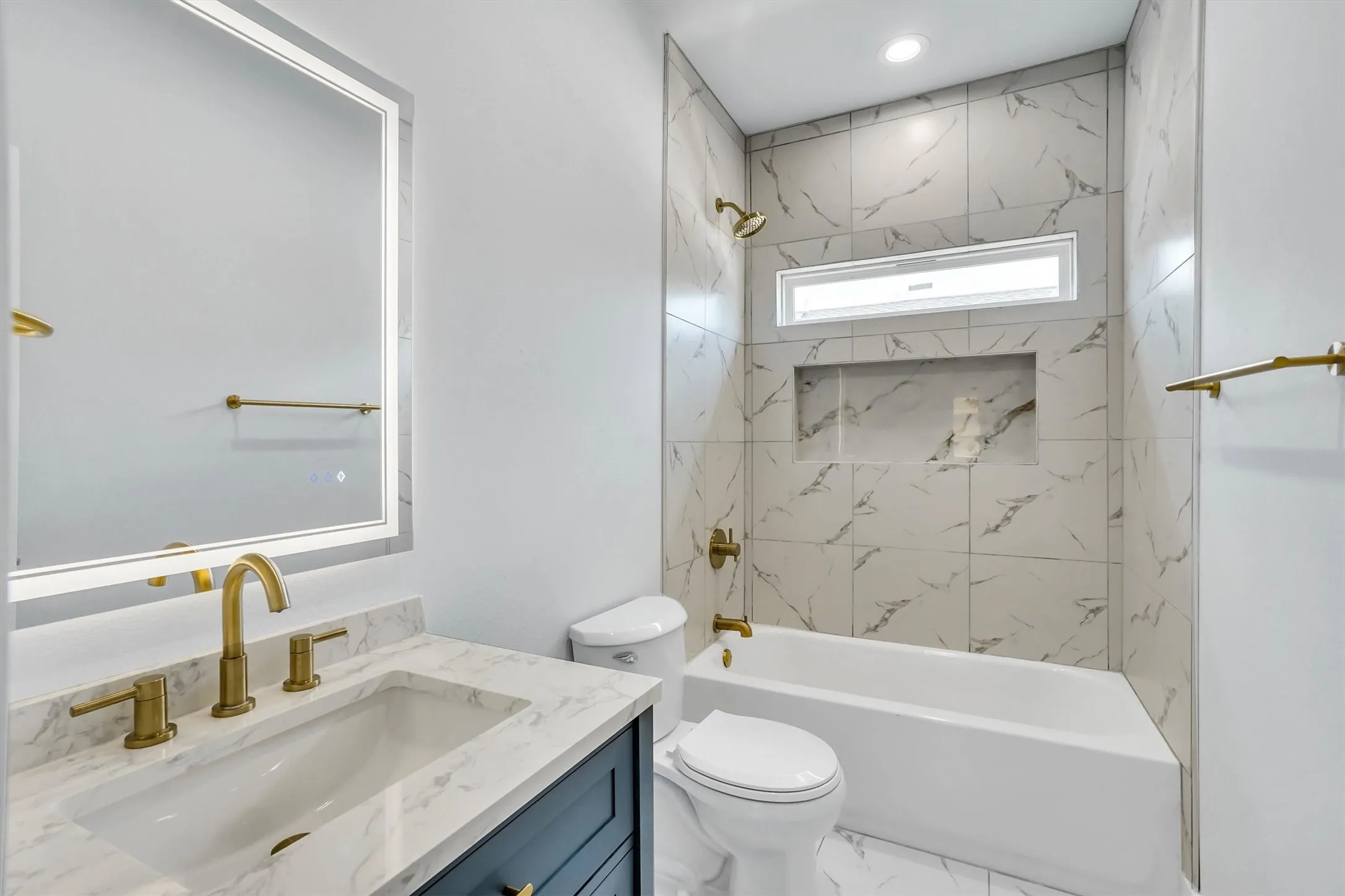 Bathroom featuring a white vanity with a marble-finish countertop, a single undermount sink, and brass-tone fixtures