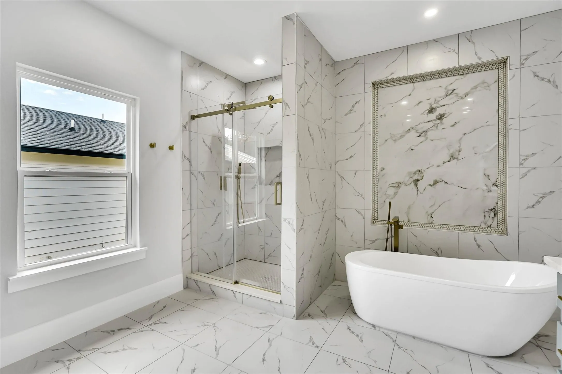 Freestanding soaking tub with a wall-mounted brass fixture