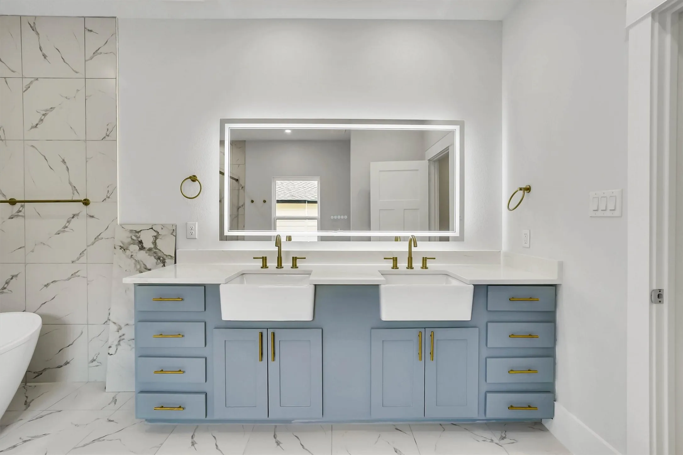 Double vanity with light gray-blue cabinetry and gold-tone hardware