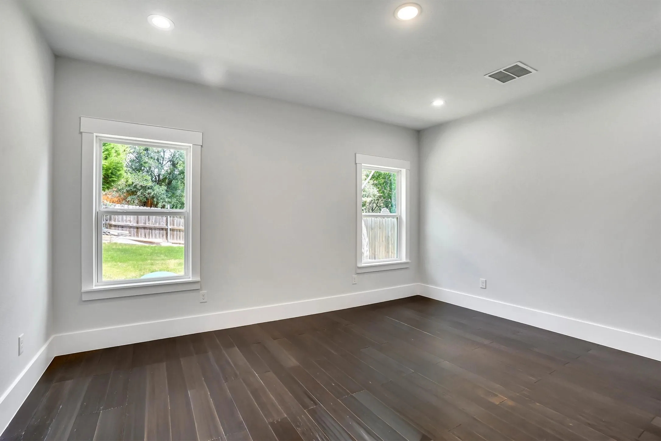 Room featuring dark wood-finish flooring, light gray wall paint, and white trim