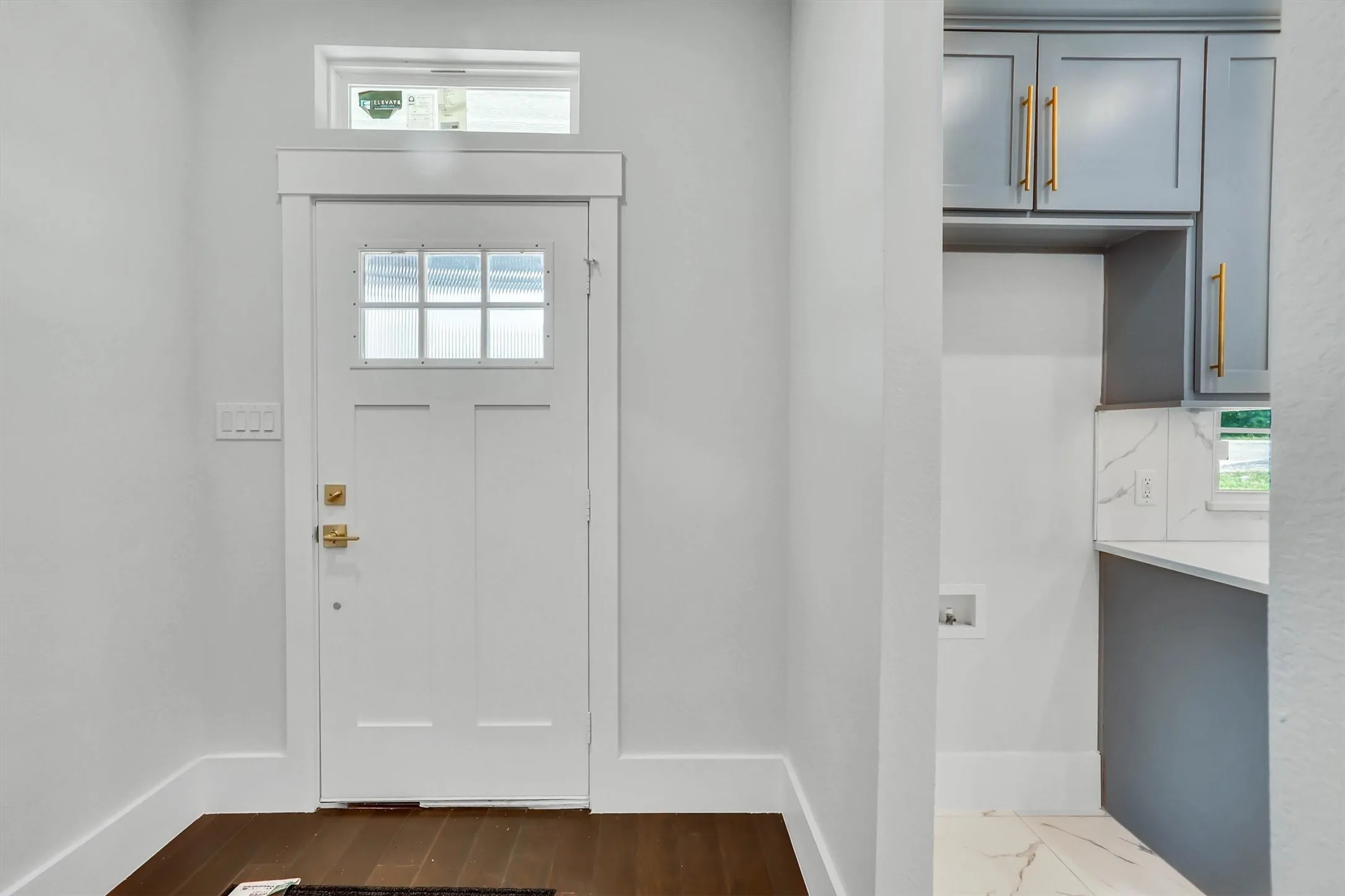 White paneled entry door with transom reeded glass window and brushed brass hardware