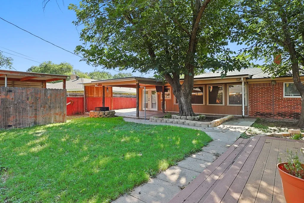 Expansive backyard featuring a lush lawn, mature trees, and a concrete pathway