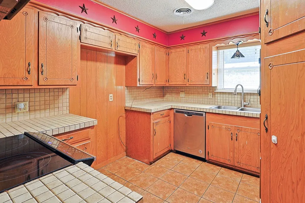 Kitchen featuring extensive wood cabinetry, tile countertops, and a dual basin sink with a high-arc faucet