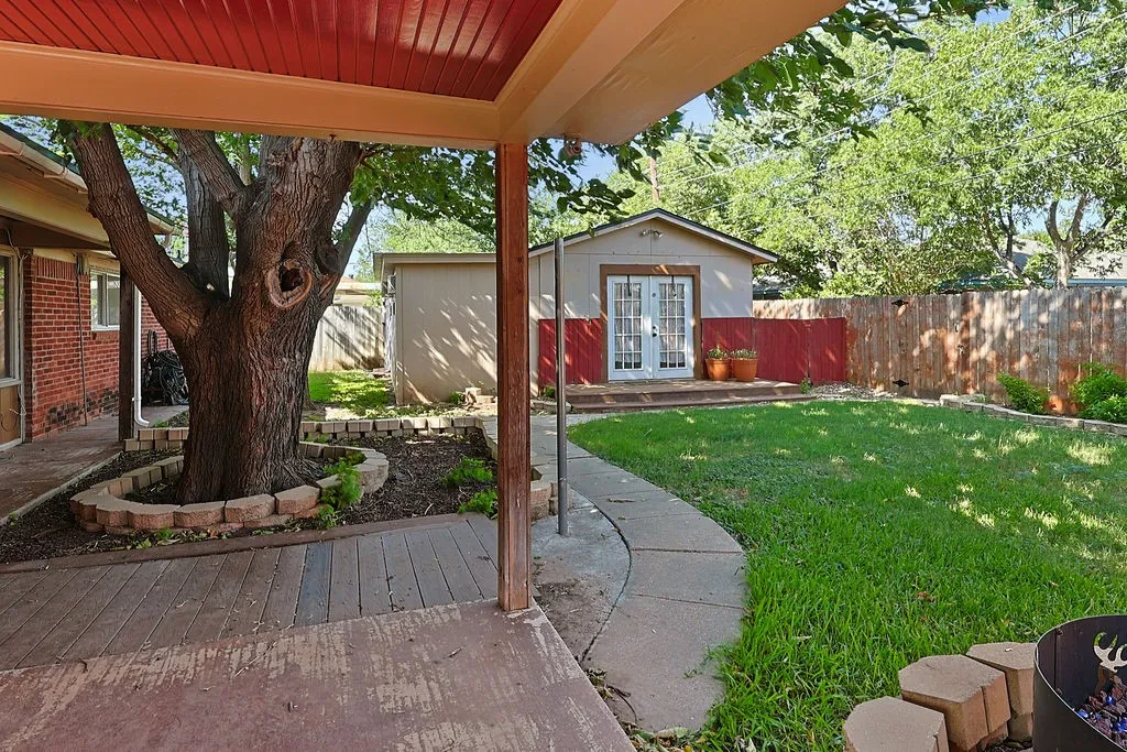 Covered patio with a wood-finish ceiling, leading to a landscaped backyard