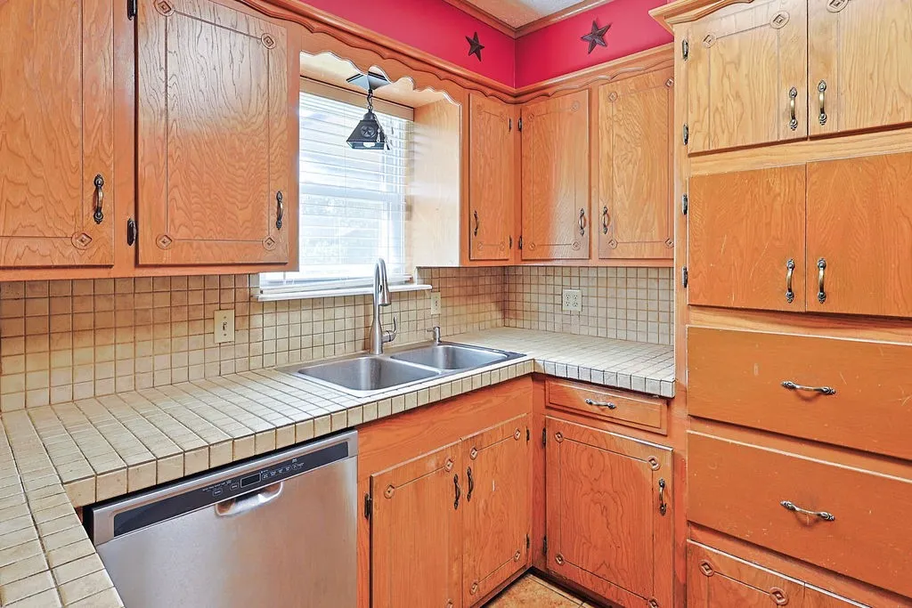 Kitchen featuring wood cabinetry with decorative trim, square tile countertops, and a complementary tile backsplash