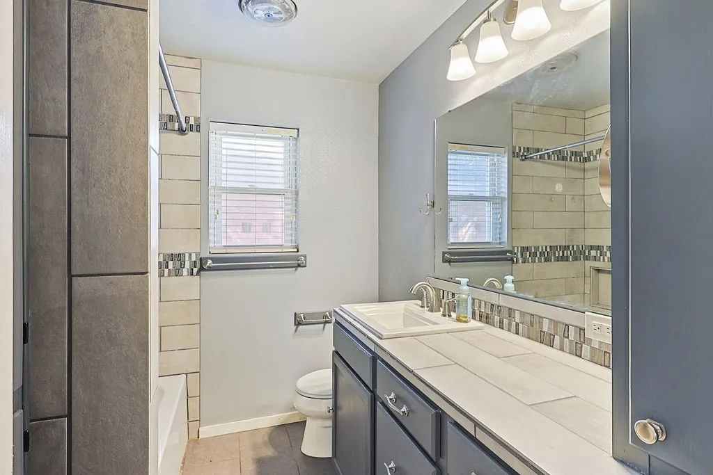 Bathroom featuring a vanity with an integrated sink, a rectangular mirror, and a tile backsplash