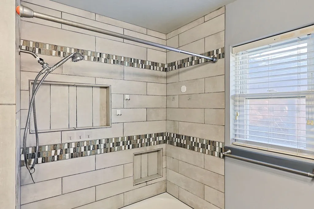 Tiled shower enclosure featuring a dual shower head system, two recessed niches, and decorative mosaic tile accents