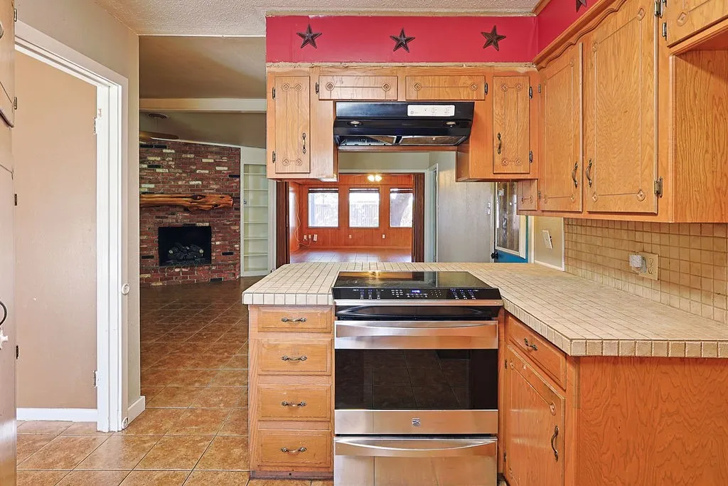 Kitchen featuring wood cabinetry, a tiled countertop, and a built-in stainless steel oven with an integrated cooktop