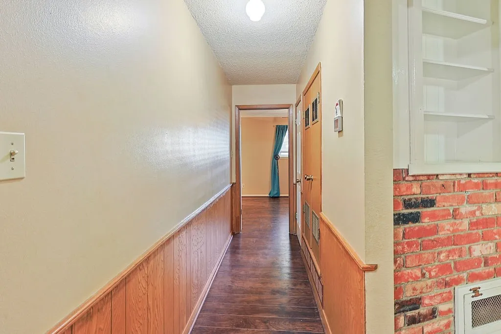 Hallway featuring wood-finish flooring, half-wall wood paneling, and an overhead light fixture