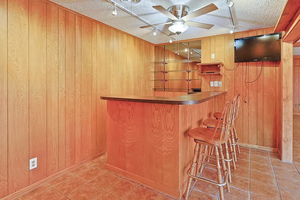 Wood-paneled room featuring a built-in bar with a brown countertop