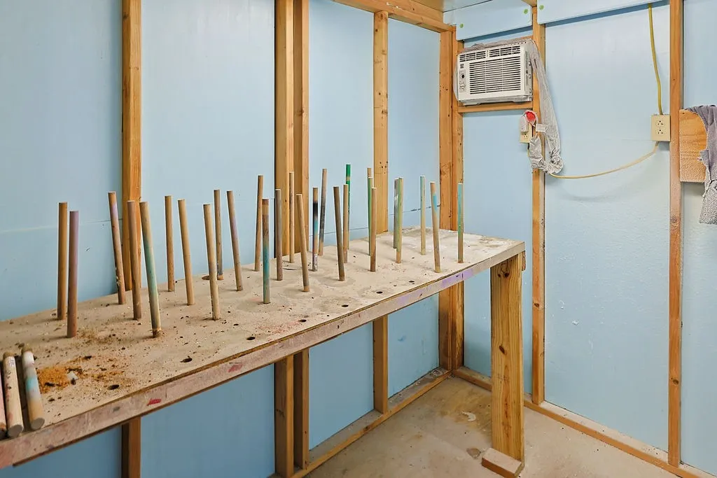 Utility room featuring exposed wooden framing, light blue walls, and a built-in workbench