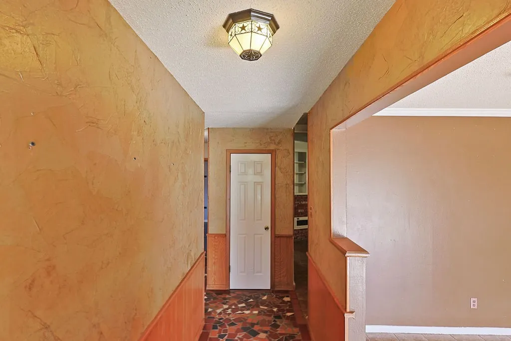Hallway featuring a mosaic-style tile floor, textured wall finish, and wood paneling