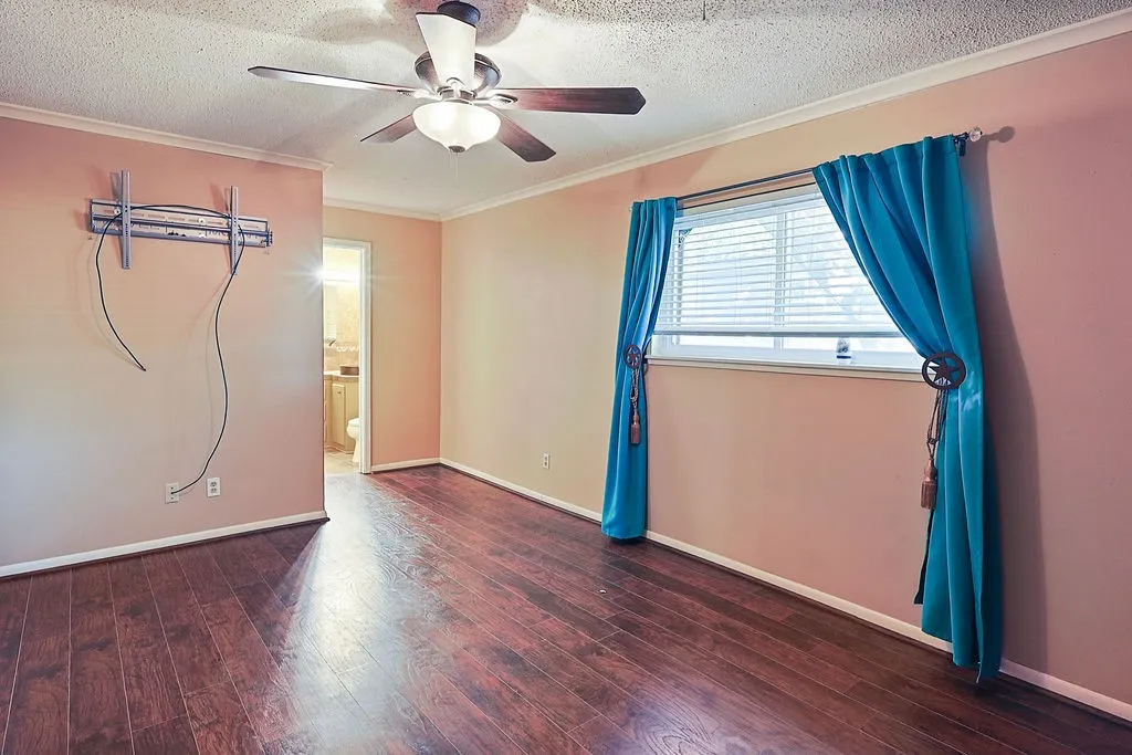 Room featuring wood-finish flooring, a ceiling fan with integrated lighting, and a window with blinds